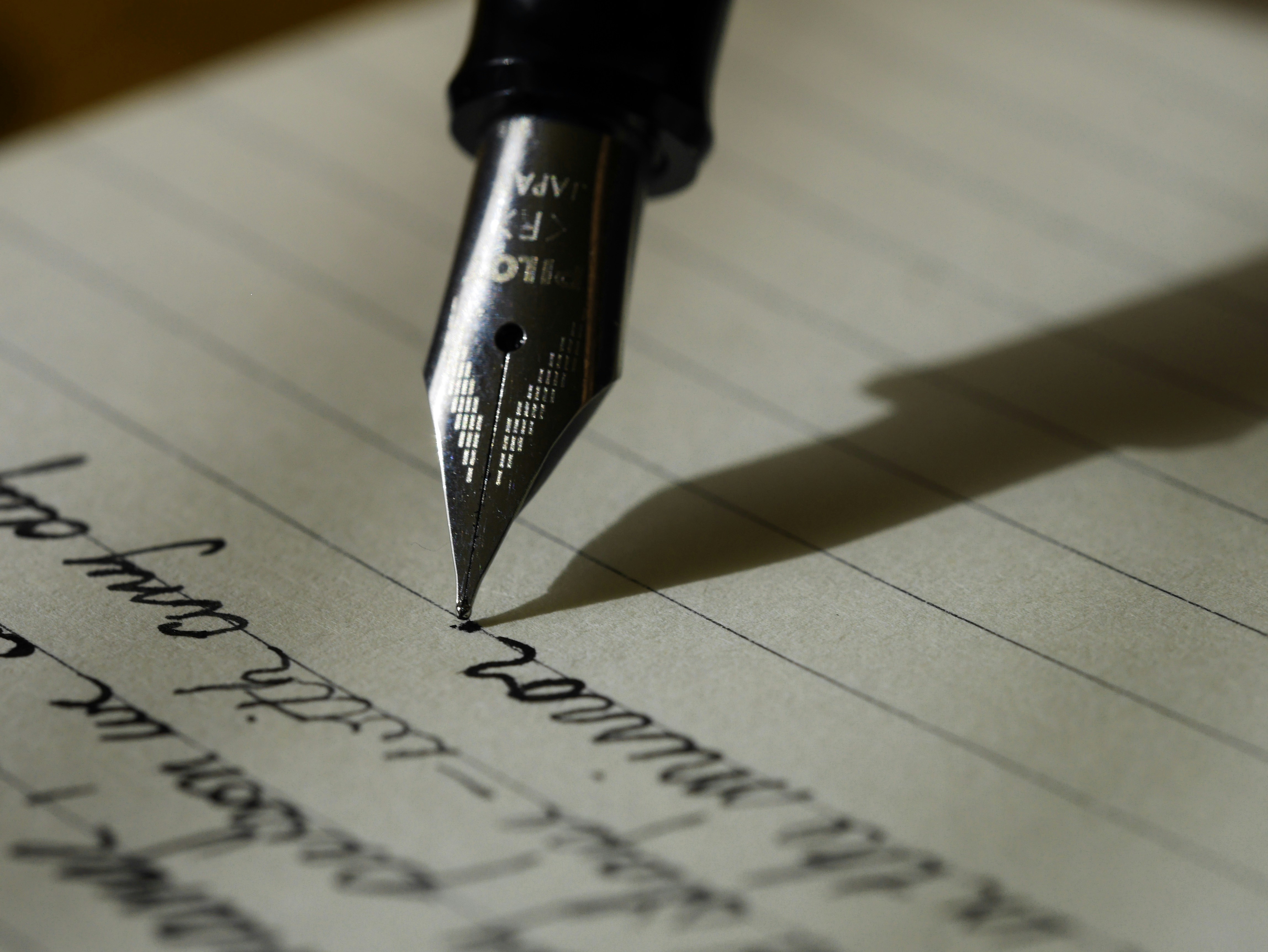 An open notebook with handwritten notes, a glass of water, and sunlit linen on a wooden desk